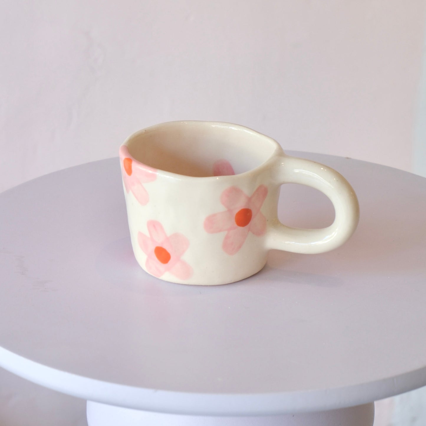 Ceramic mug with floral design on a white pedestal